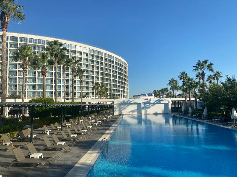Sunny resort swimming pool with palm trees — TUI Beachtime code beach holidays