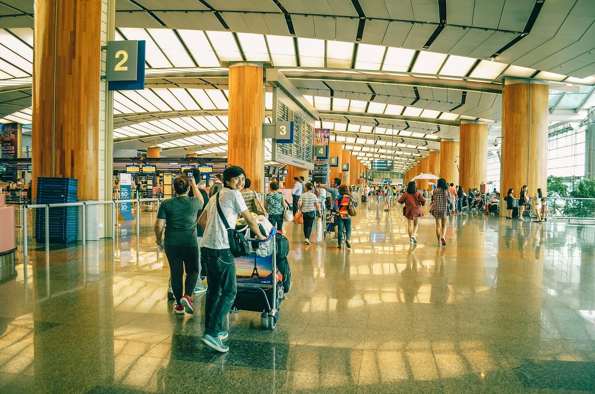 Families with luggage walking through a bright, modern airport departure hall