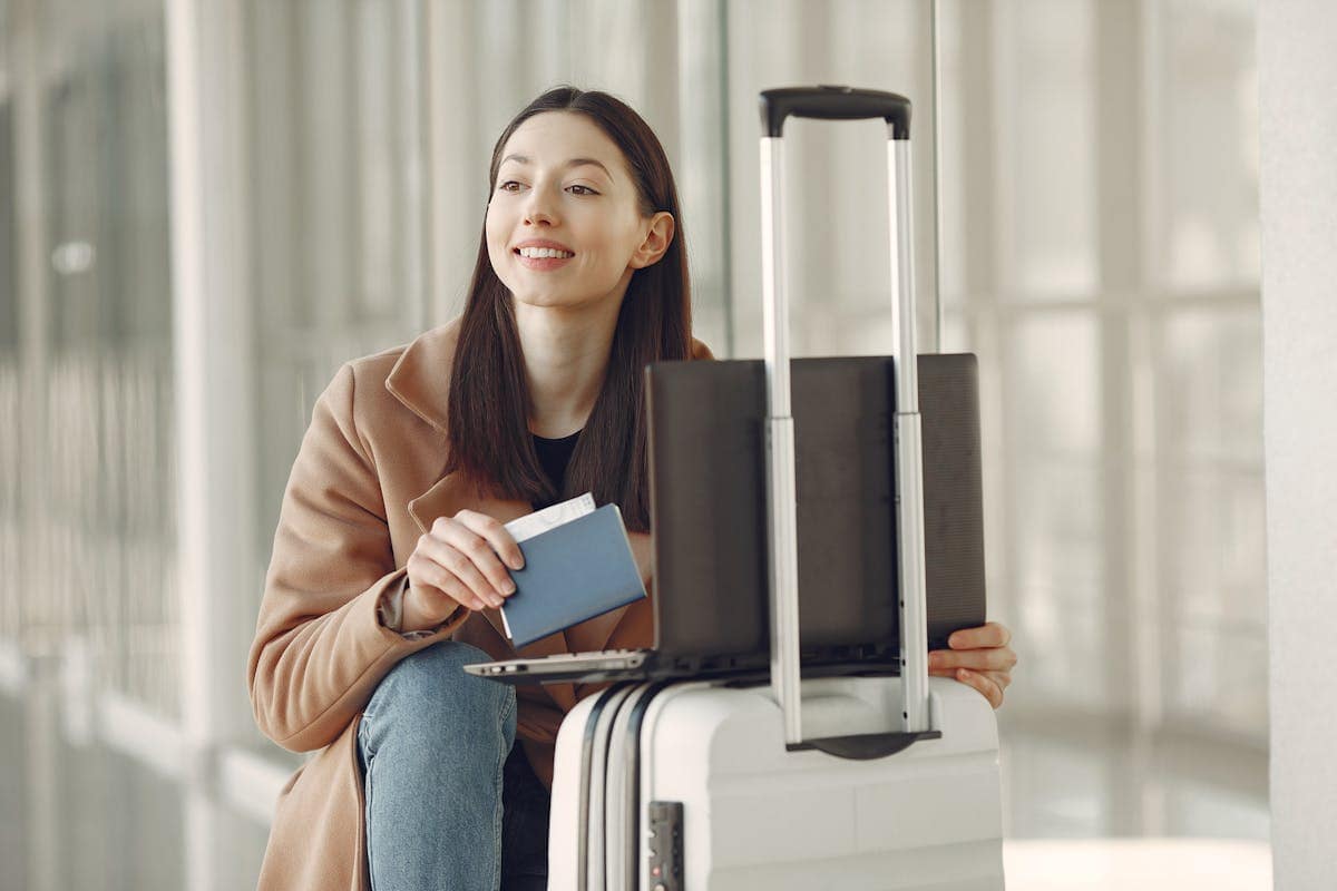Traveller with passport and laptop checking flight prices at airport