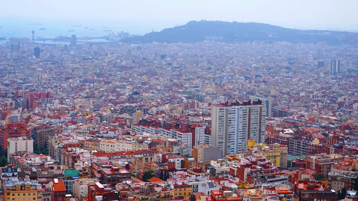 Aerial panoramic view of Barcelona's distinctive urban grid and the coastline beyond, Catalonia, Spain