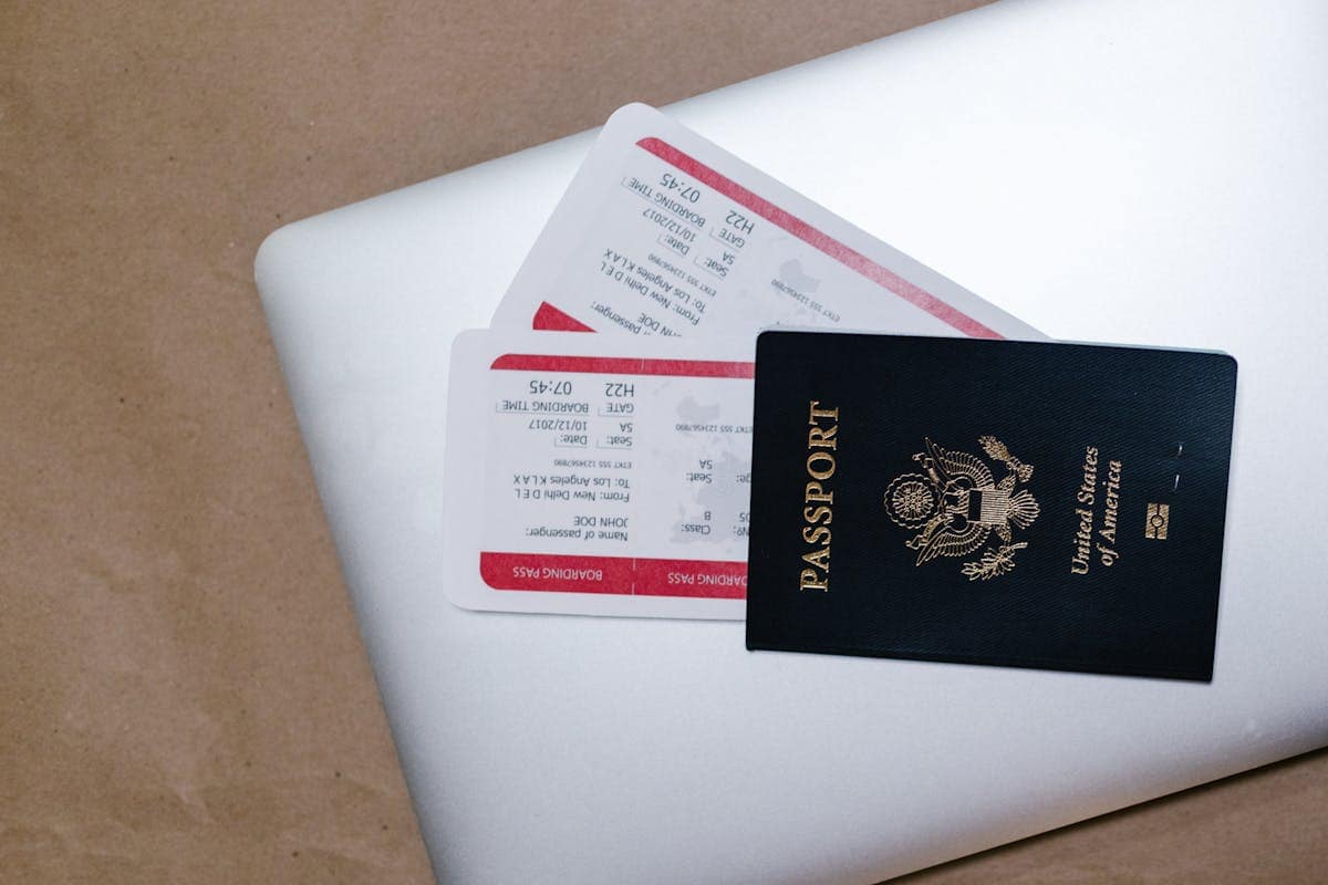 A passport and airline tickets placed on top of an open laptop, representing flight and holiday booking preparation