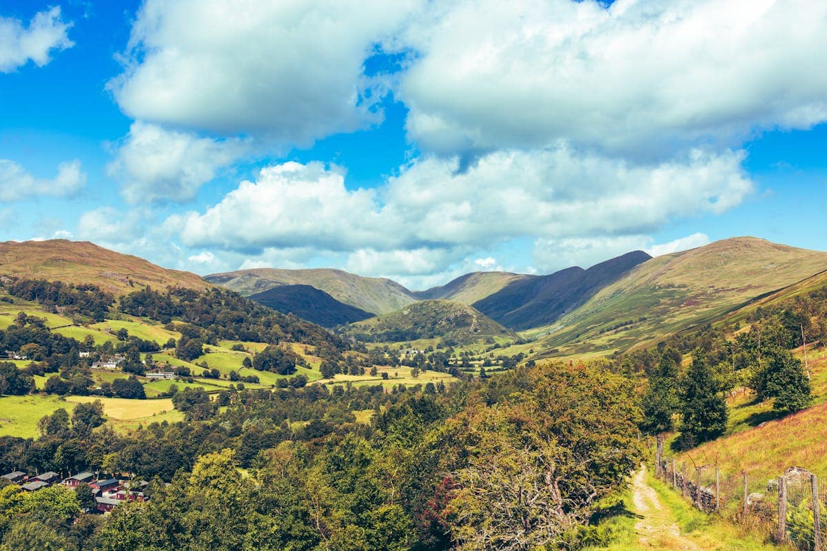 Troutbeck Valley in the Lake District, a green valley surrounded by fells under a blue sky