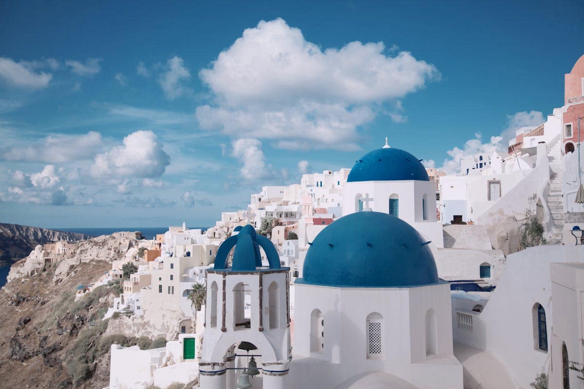 Blue-domed churches and whitewashed buildings on the caldera edge in Santorini, Greece