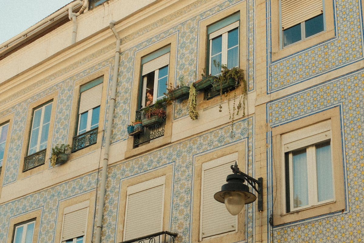 Traditional azulejo tile facade on a Lisbon apartment building with window boxes and a street lamp