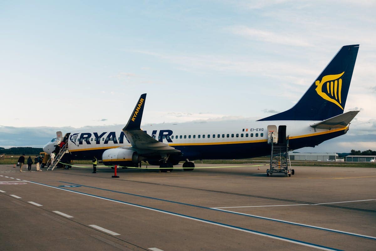 Passengers boarding a Ryanair Boeing 737 via stairs at a sunny airport