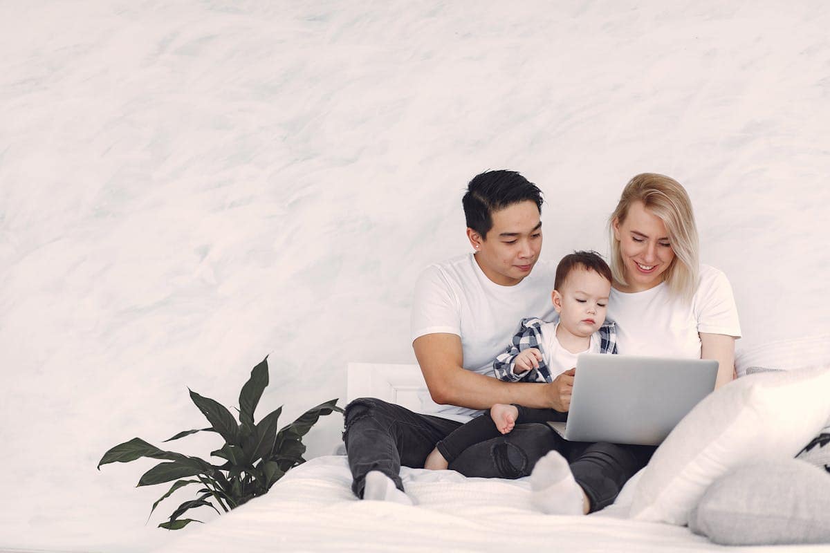 A couple with their child looking at a laptop screen while planning a school holiday hotel booking