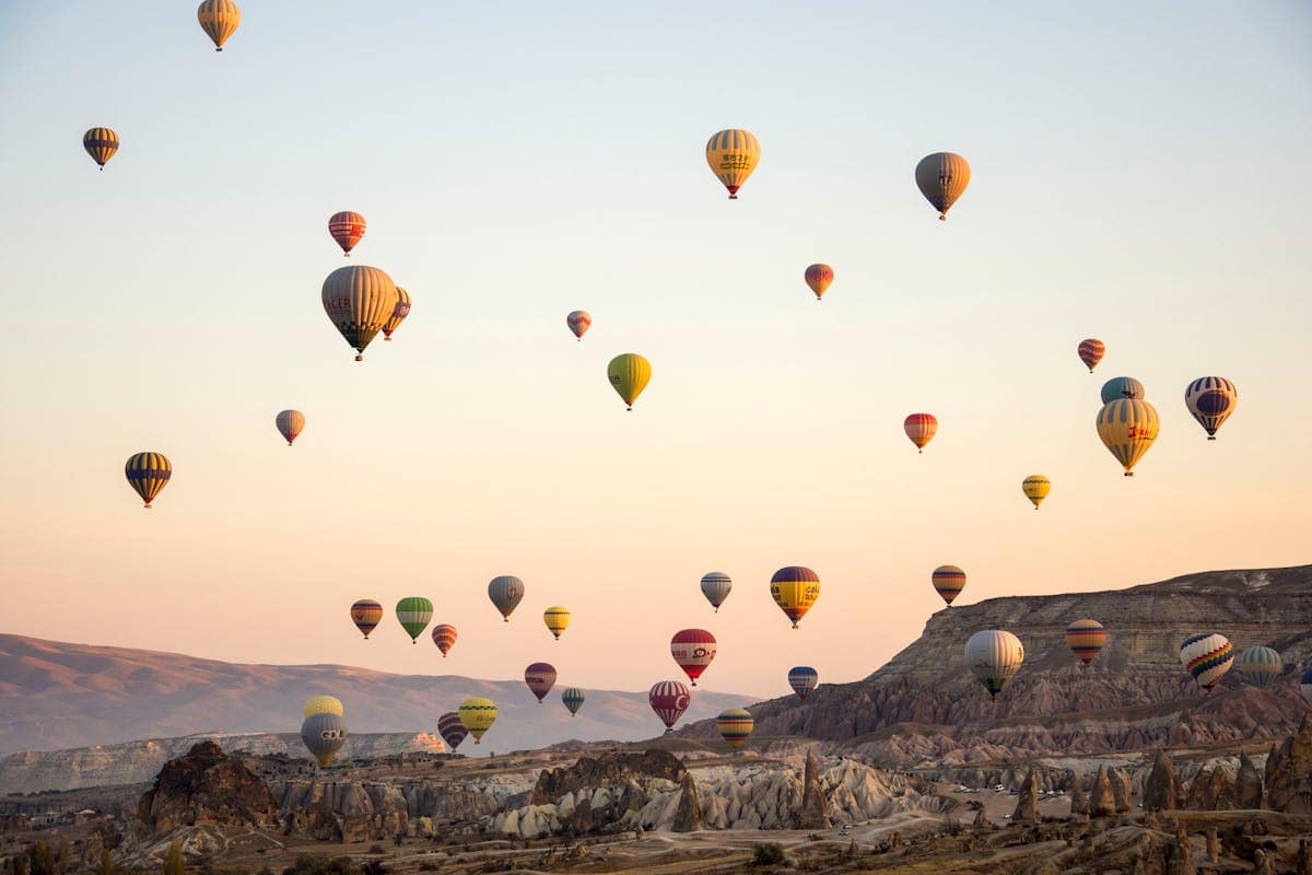 Hot air balloons rising over the fairy chimneys and volcanic rock formations of Cappadocia at sunrise, Turkey