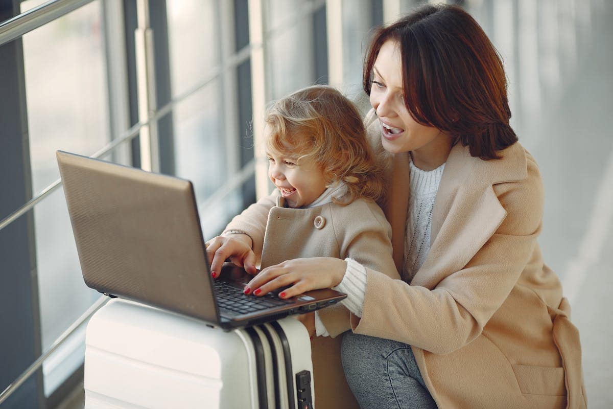 Mother and daughter booking flights on a laptop at the airport