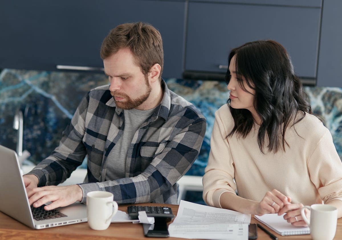 Couple planning a trip together, comparing flight prices on a laptop at home