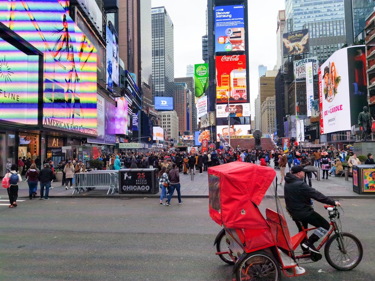 Times Square at daytime with crowds of visitors and colourful LED billboards