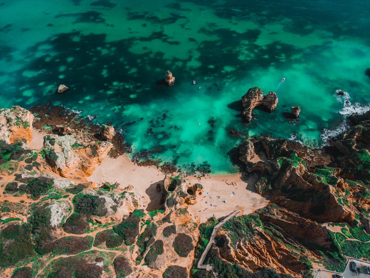 Aerial drone view of Algarve coastline with turquoise sea and orange limestone cliffs