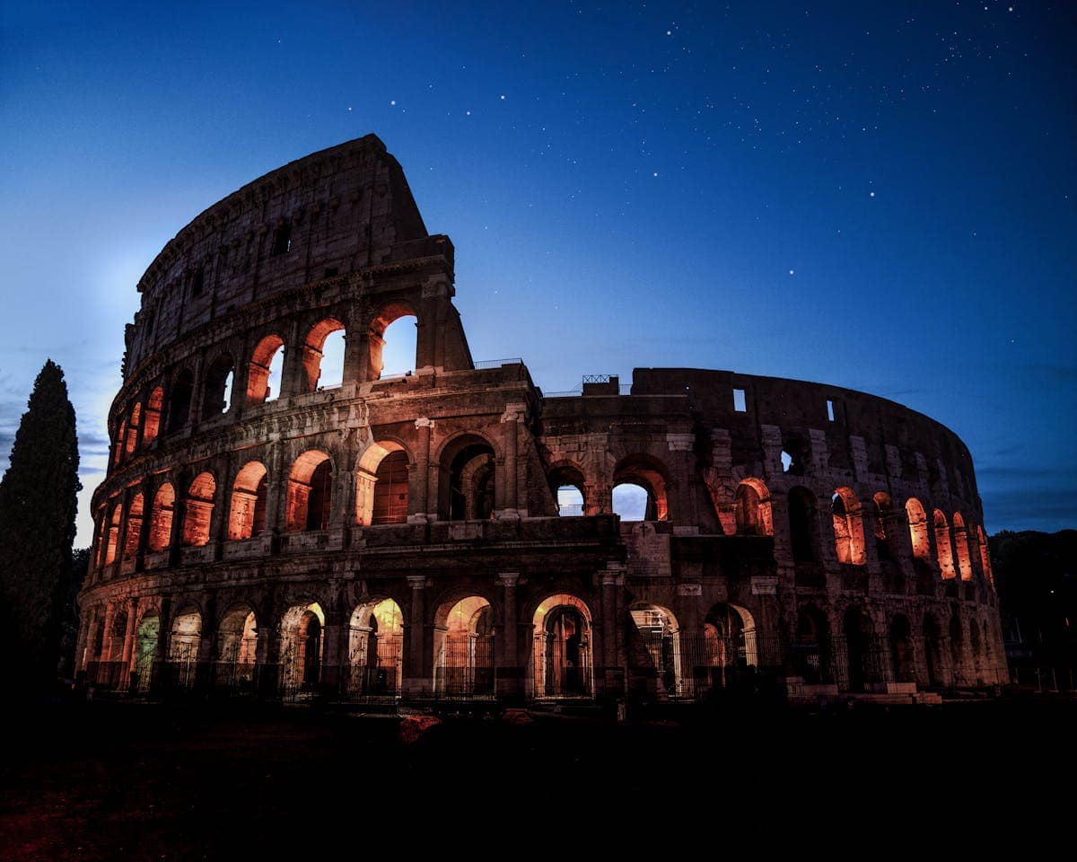 The Colosseum in Rome at night, lit against a dark sky