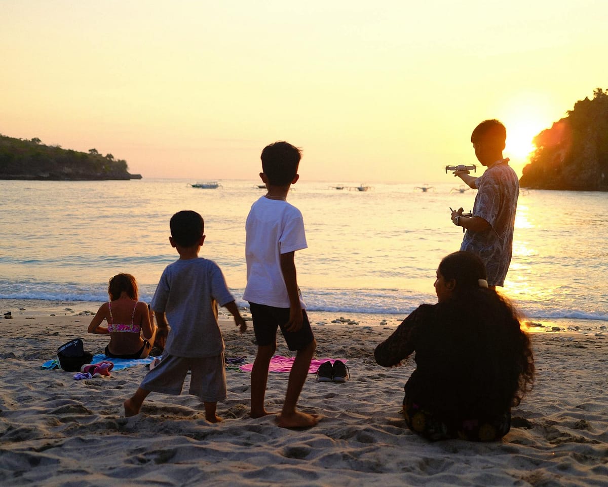 A family watching a beautiful sunset on a beach with children playing in the foreground