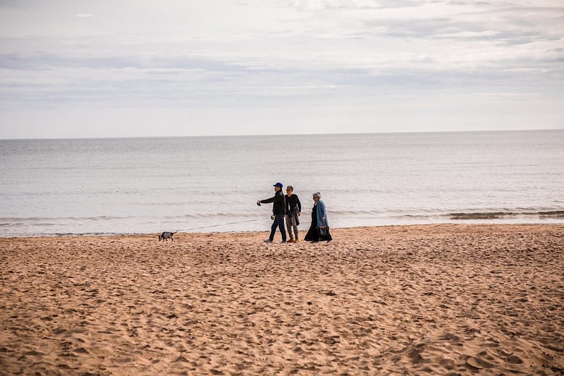 Family walking along Bournemouth beach on a sunny day, a popular UK school holiday destination
