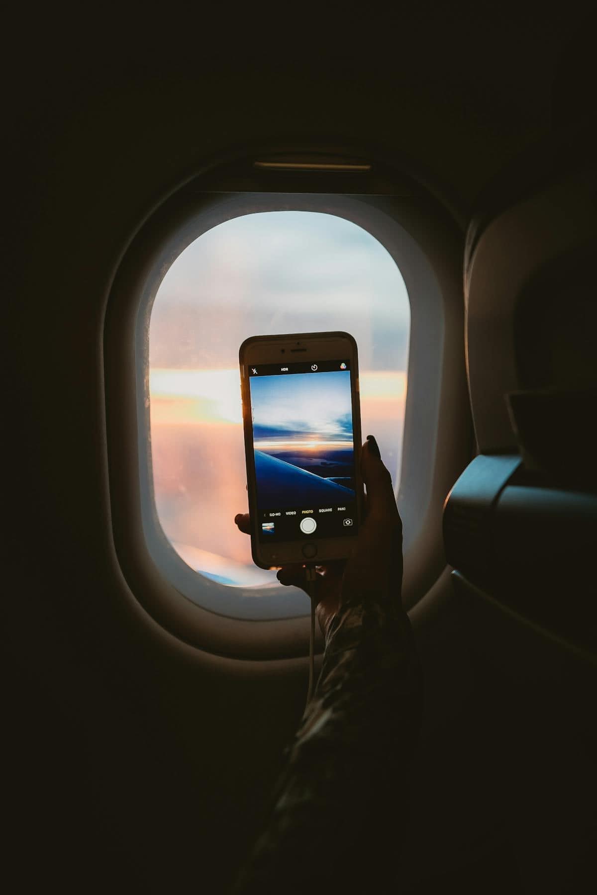 Person holding smartphone inside an airplane cabin while in flight