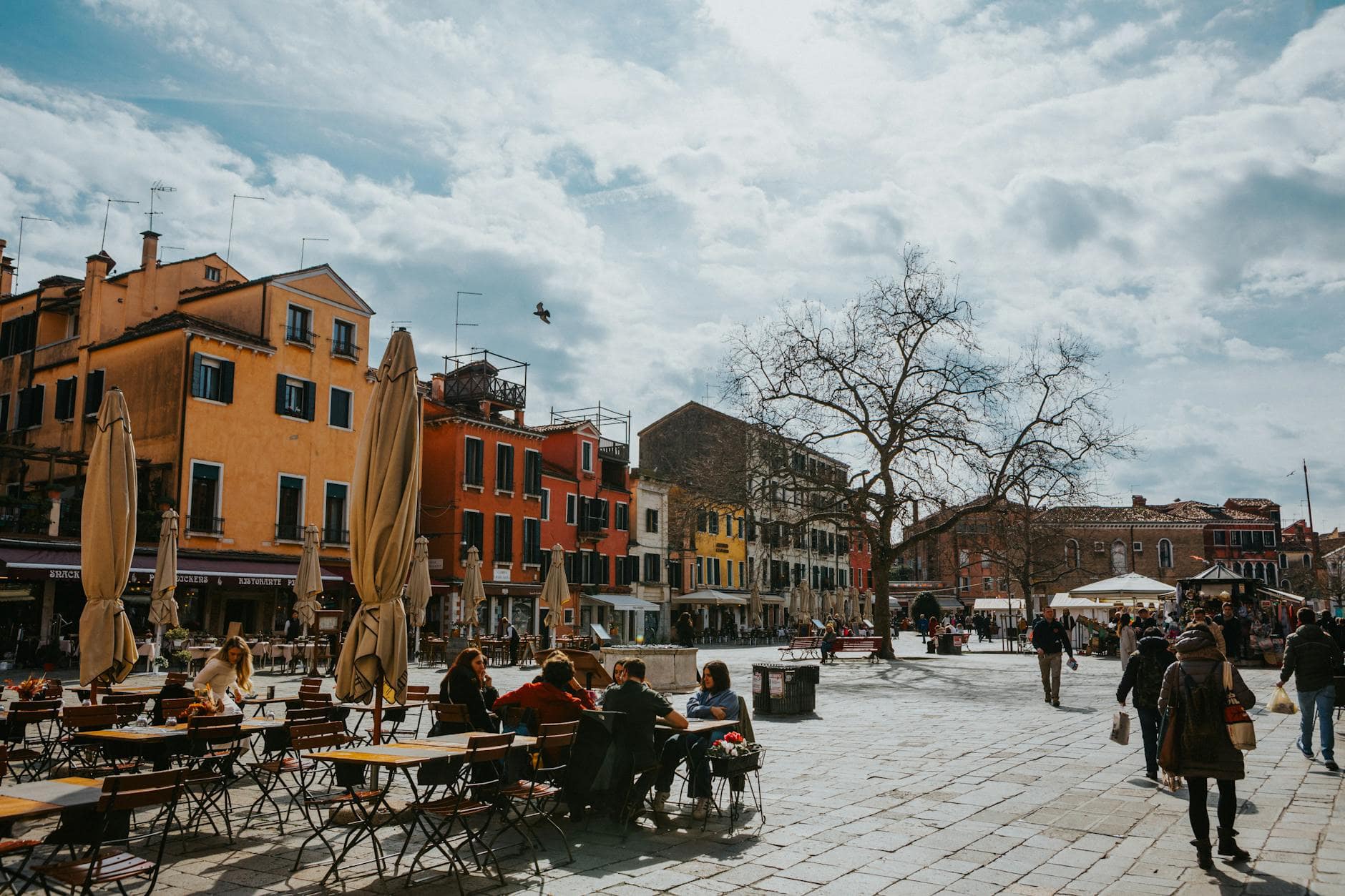 People enjoying a sunny day at a colourful piazza in Italy, ideal for an Easter city break
