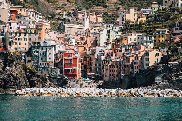 Scenic view of a Cinque Terre village harbour with colourful boats on clear blue water